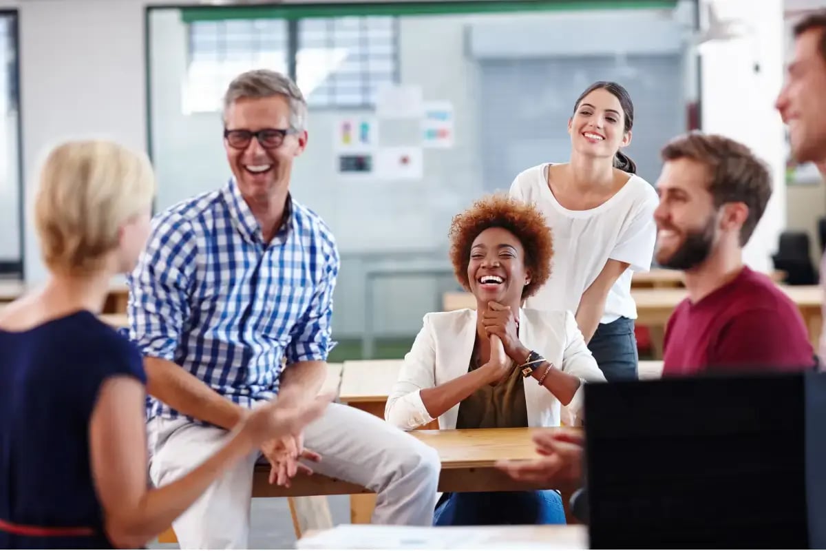 Happy employees interacting in an office that supports workplace wellness